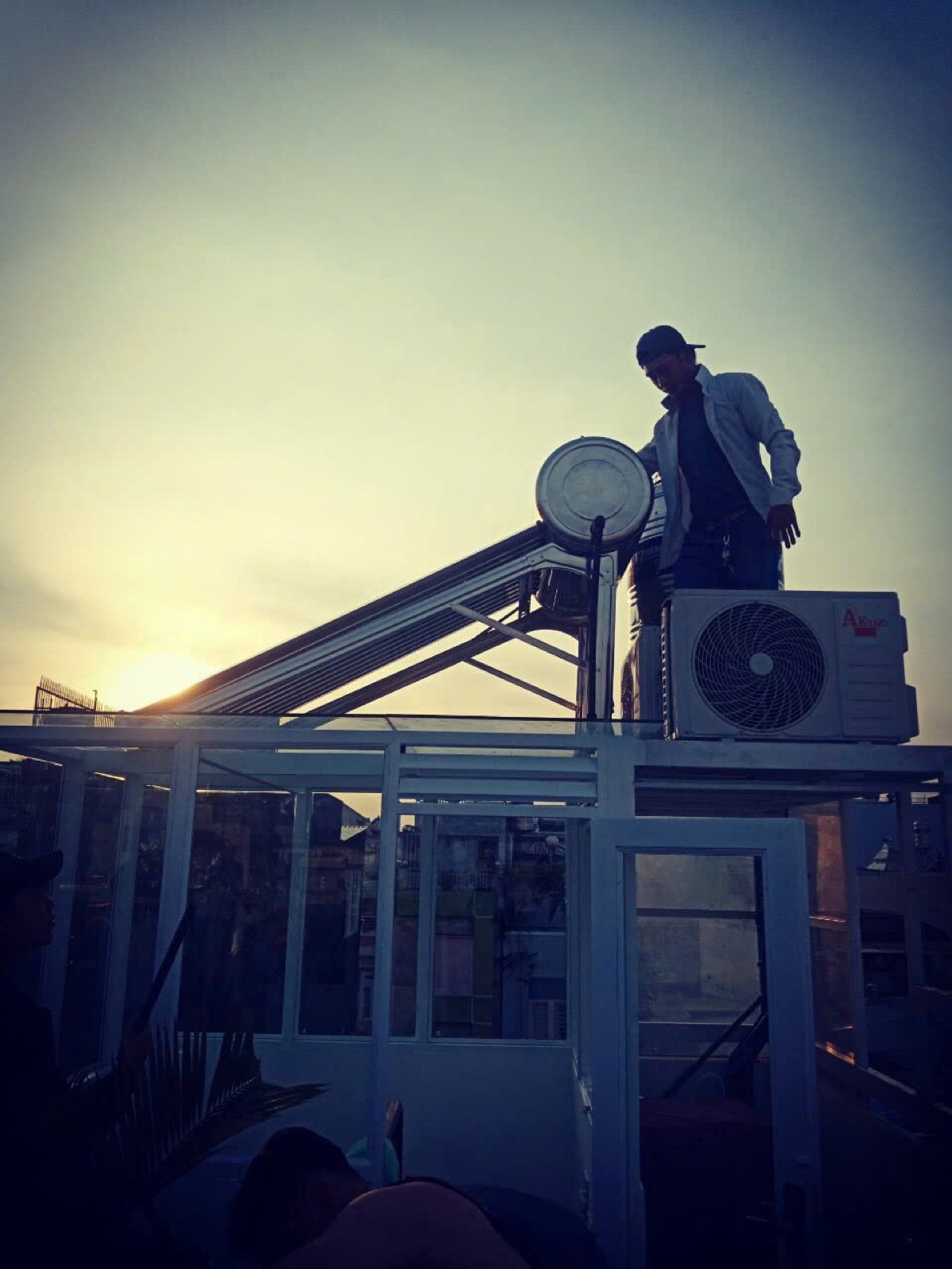 Kỹ thuật viên Văn Tùng Solar kiểm tra máy nước nóng năng lượng mặt trời trên mái.